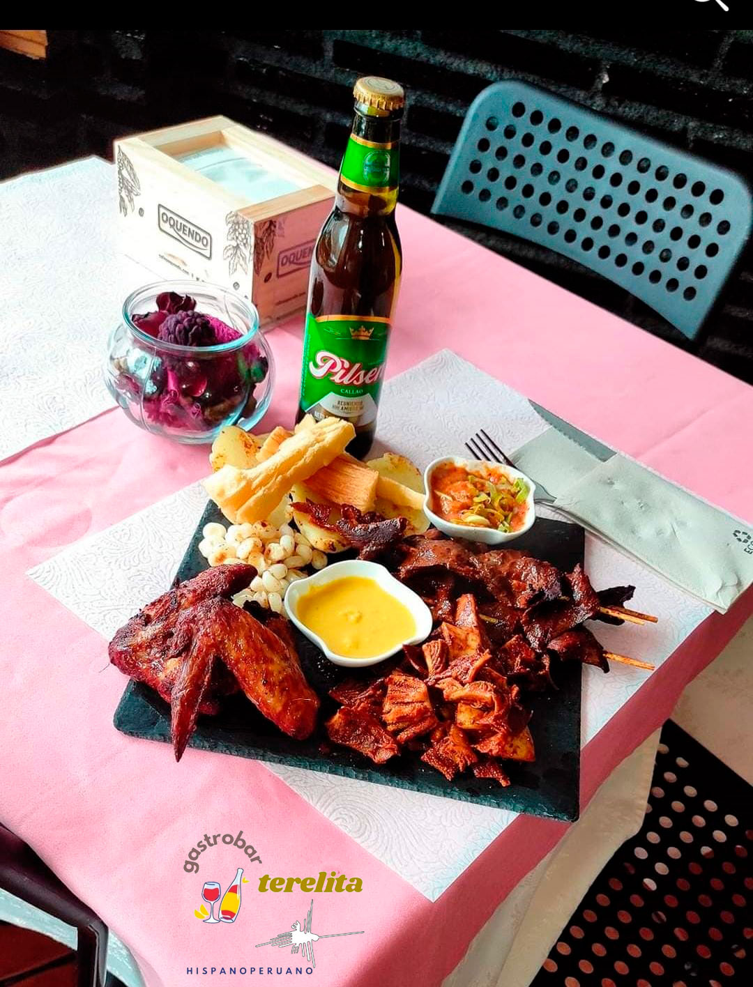 plato de pizarra con alitas de pollo, pinchos de carne y salsas con una cerveza